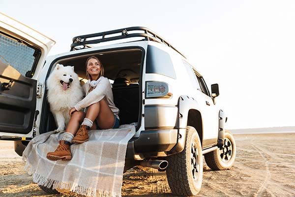 Woman sitting in her car with her dog in the desert