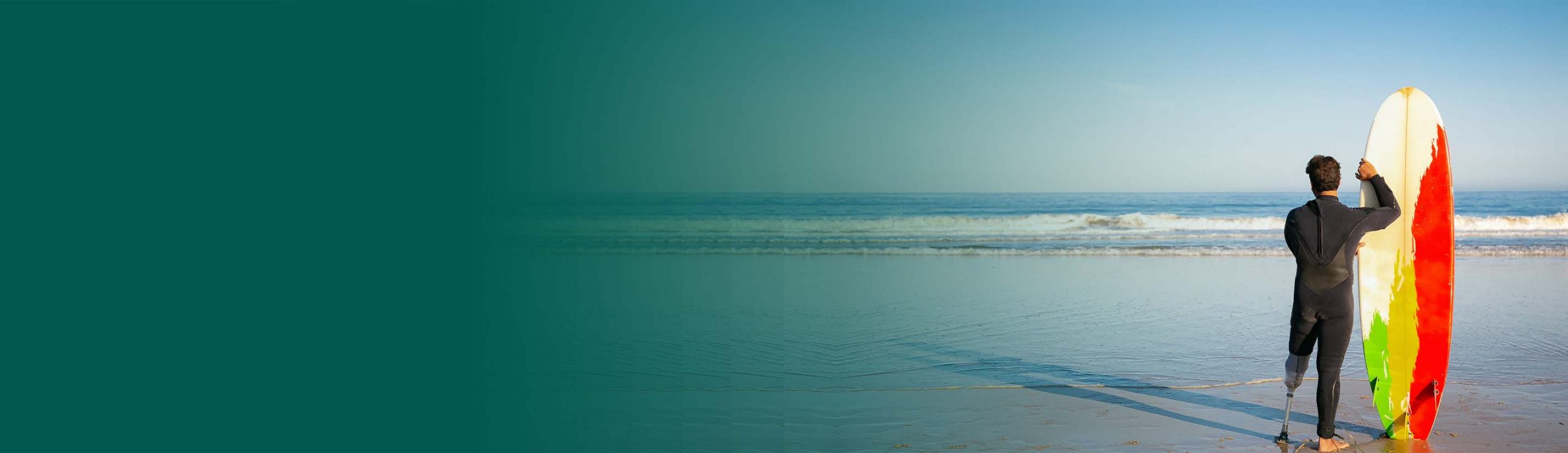 Surfer with prosthetic leg standing on the beach with a surfboard